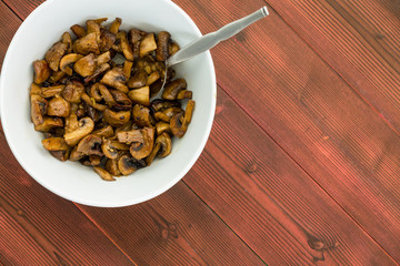 Overhead view of cooked mushrooms in a white bowl