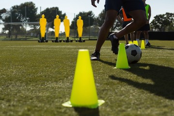 Soccer player dribbling the ball through cones