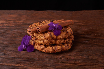 Closeup on stack of chocolate Chip ion wood background with live flowers - cookies for mom on mothers day top view. Selective focus