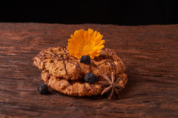 Closeup on stack of chocolate Chip ion wood background with live flowers - cookies for mom on mothers day top view. Selective focus