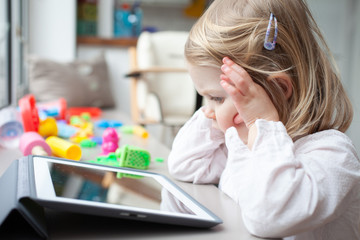 Obraz na płótnie Canvas Female toddler playing on a tablet