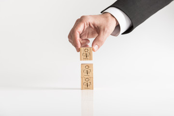 Businessman arranging wooden blocks with human icons