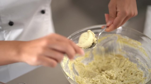 4K cooking footage, close up female cook forming dumplings with spoons and putting into boiling water in kitchen pot
