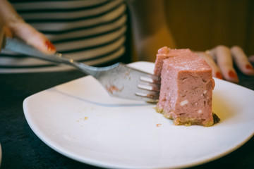 Close-up of a stone table with a cup of coffee and a delicious piece of cake. Model cuts the cheesecake with a fork. Fashionable new interior. Perfect background for websites or coffee shops