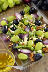 Salad with various grapes, goat cheese, purple onion, arugula and walnuts