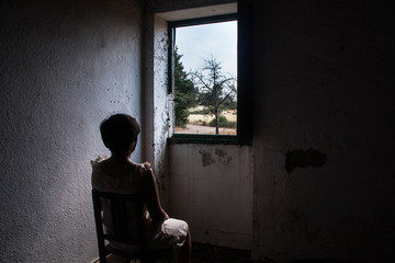 A lonely woman sitting on a worn out house