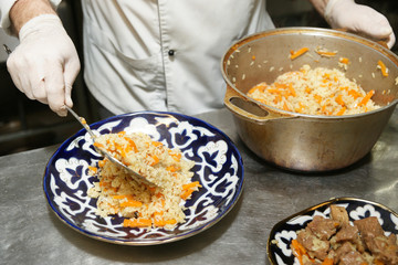 Chef is serving pilaf in restaurant kitchen