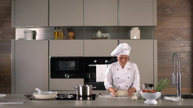 4K cooking footage, woman female chef cook in white cooks jacket preparing fresh dough for italian gnocchi in modern kitchen
