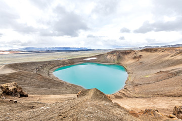 Panoramic view on Viti Crater of Krafla caldera geothermal formation with small lake of blue, turquoise, green water, mountains, snow during summer