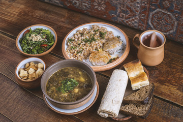 Middle Eastern cuisine dishes in ceramic plates on a wooden table. Lentil soup, salad with lettuce...