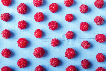 Many fresh raspberries on blue wooden background. Bright texture for design. Top view