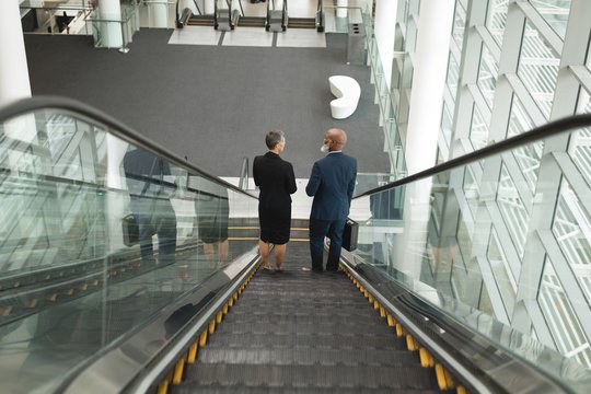 Businessman and businesswoman going down on an escalator