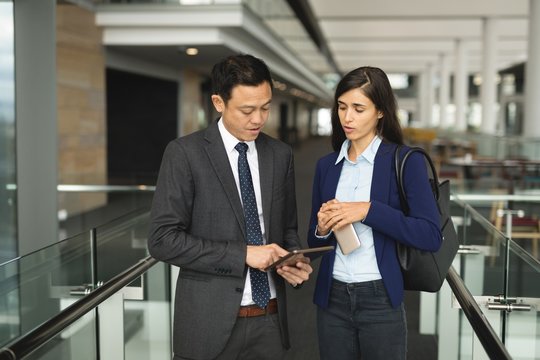 Businessman and businesswoman discussing over a digital tablet