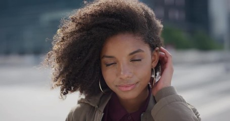 portrait beautiful young african american woman smiling running hand through hair independent black female enjoying calm summer lifestyle in city wind blowing afro hairstyle