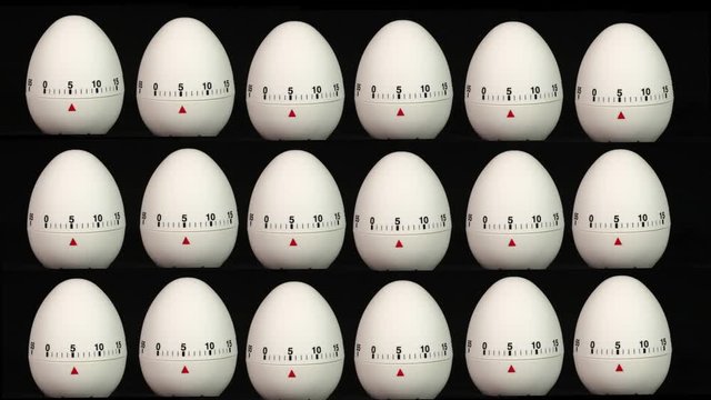 White kitchen egg timers the same size in rows on a black background counting down to zero time lapse.