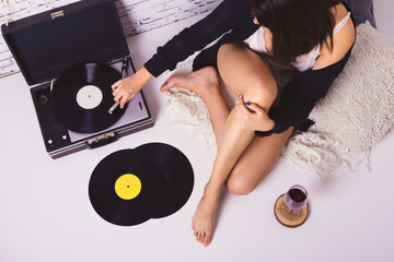 Young woman enjoying at cozy home listening to vinyl records and drinking wine. High angle view,...