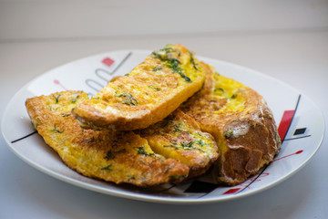 Fried bread in an egg with dill. Fried bread on a plate. Breakfast - bread and eggs.