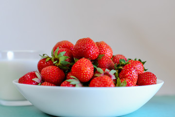 white plate with fresh strawberries and a glass of milk. horizontal orientation.