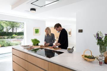 Couple preparing a meal on the countertop of their modern kitchen.
