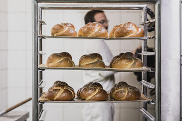 Baker standing behind trays of fresh baked bread