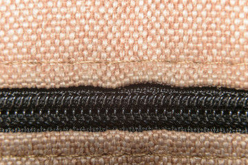 Black closed zipper on a beige fabric