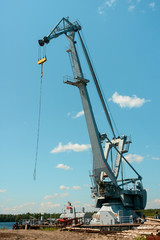 Huge industrial cargo crane at a port over blue sky background