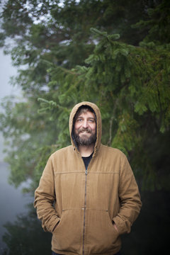 Man in hooded jacket stands on a dock in Fletcher Bay on a foggy morning.