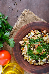 Fototapeta na wymiar Tabbouleh - hot salad of couscous, meat, fried vegetables and parsley in a clay bowl. Lebanese cuisine. The top view