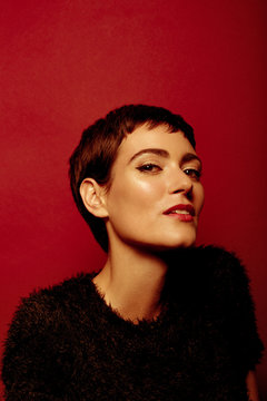 Beautiful and confident short haired woman portraits in her 30s shot in studio isolated over red background