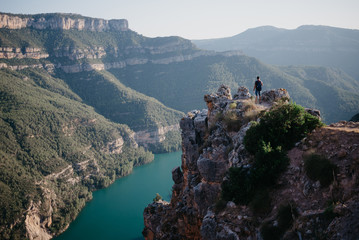 A man with the backpack staying on the top of the rock in the canyon on the sunset in Spain. Traveler on the Canyon