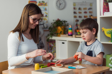 Fototapeta premium Teacher and child playing with didactic colorful toys indoors - preschool
