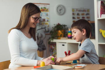 Teacher and child playing with didactic colorful toys indoors - preschool