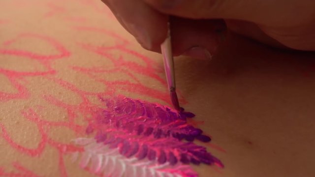 Professional artwork on a humans body. Filling the pattern by purple coloured smears.