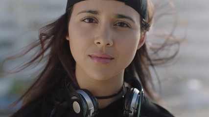 close up portrait of cute young hispanic girl looking up at camera serious calm wind blowing hair wearing trendy fashion on sunny day