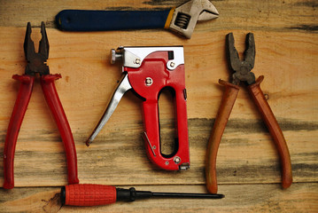 old home tools on a wooden background, pliers, tongs, stapler