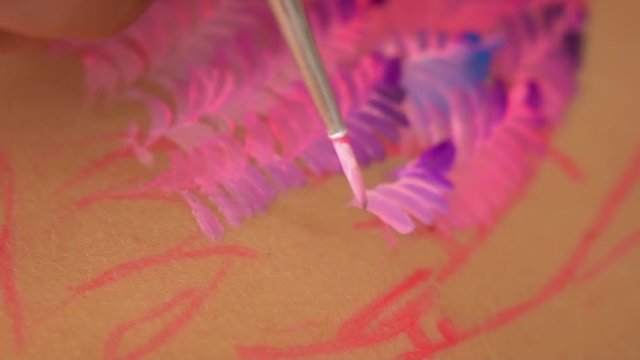 Artists work on body art design. Smearing vivid tones on skin.