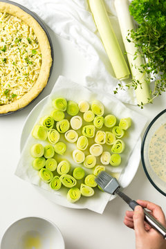 Brushing melted butter over steamed leeks for a tart