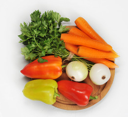 Fresh seasonal vegetables on wooden board. On the photo there is onion, carrots, sweet peppers, a bunch of parsley. Set for making peppers stuffed with carrots. White background. View from above.