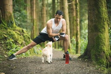 Fit man doing stretching exercise with his dog