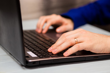 Young man working with laptop, man's hands on notebook computer, business person at workplace