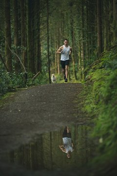 Man jogging in forest with his dog