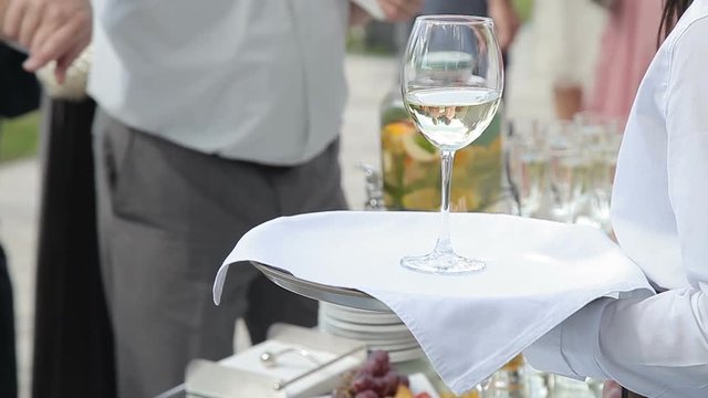 The waiter holds a tray with a glass of wine