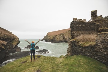 Female hiker with arms spread standing at the sea coast