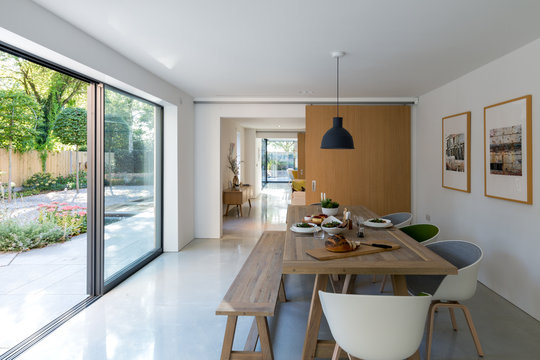 Contemporary dining room with views to the garden through large glass areas. Table set for lunch.