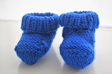 Gifts for a new born baby boy: yellow baby wool shoes, a handmade woven white pullover and a golden gift box