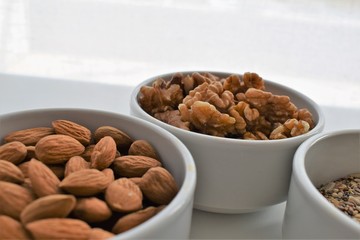 Three containers with almonds, walnuts and a mixture of sunflower seeds, chia and sesame