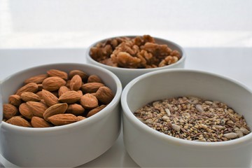 Three containers with almonds, walnuts and a mixture of sunflower seeds, chia and sesame