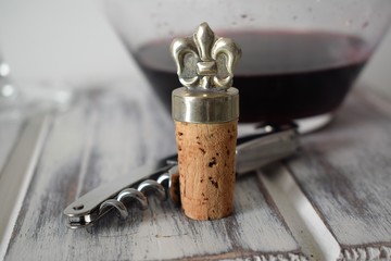 Cork and buckler over a wooden table with a decanter with red wine over it