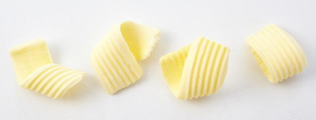 Four Textured Curls of Butter on White Background