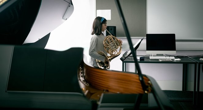 Schoolgirl playing french horn in music school